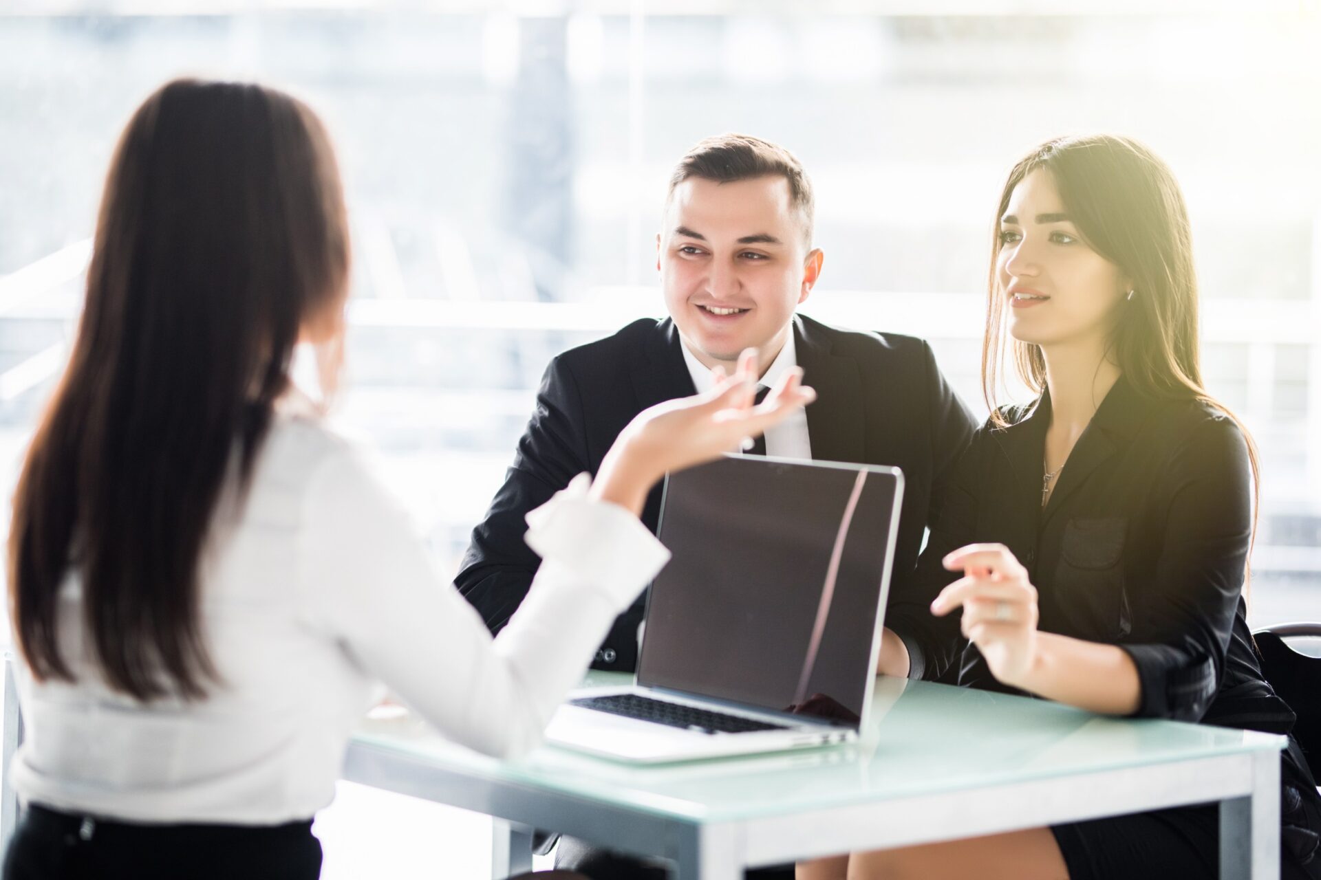 Young couple sitting at a desk in the office of their adviser discussing about accounting Young couple sitting at a desk in the office of their adviser discussing about accounting